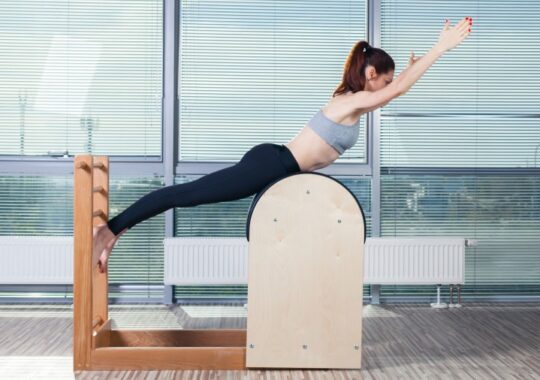 47935424 - pilates, fitness, sport, training and people concept - smiling woman doing  exercises on ladder barrel.